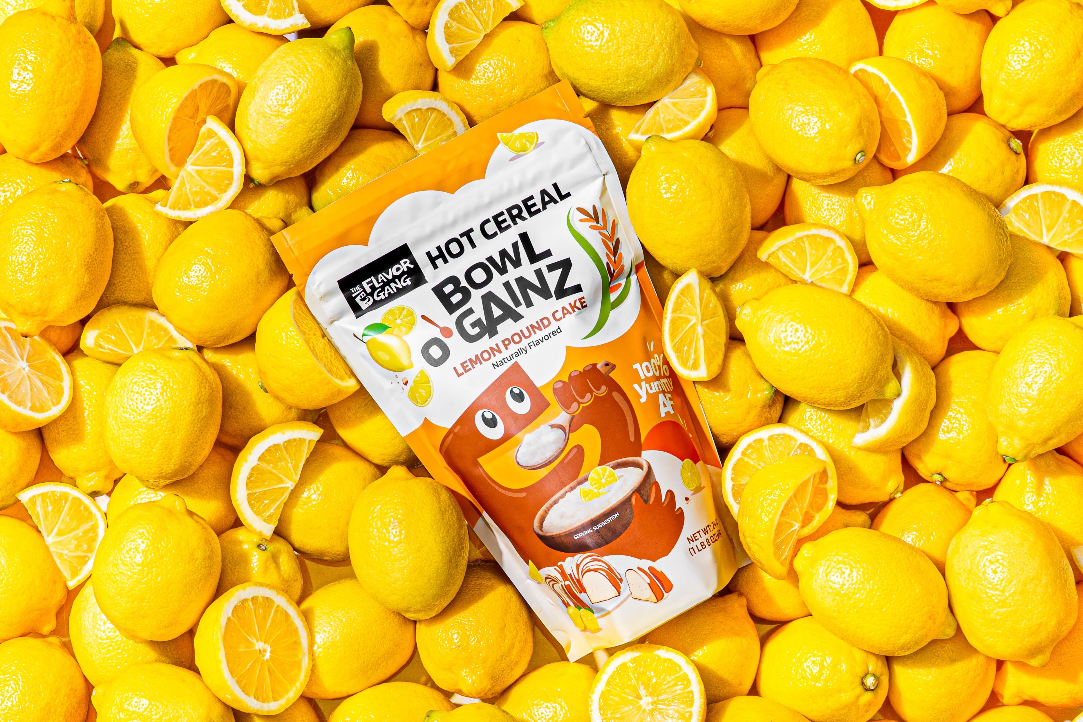 Bowl O' Gainz Lemon Pound Cake hot cereal pouch by The Flavor Gang resting on a bed of fresh whole and sliced lemons