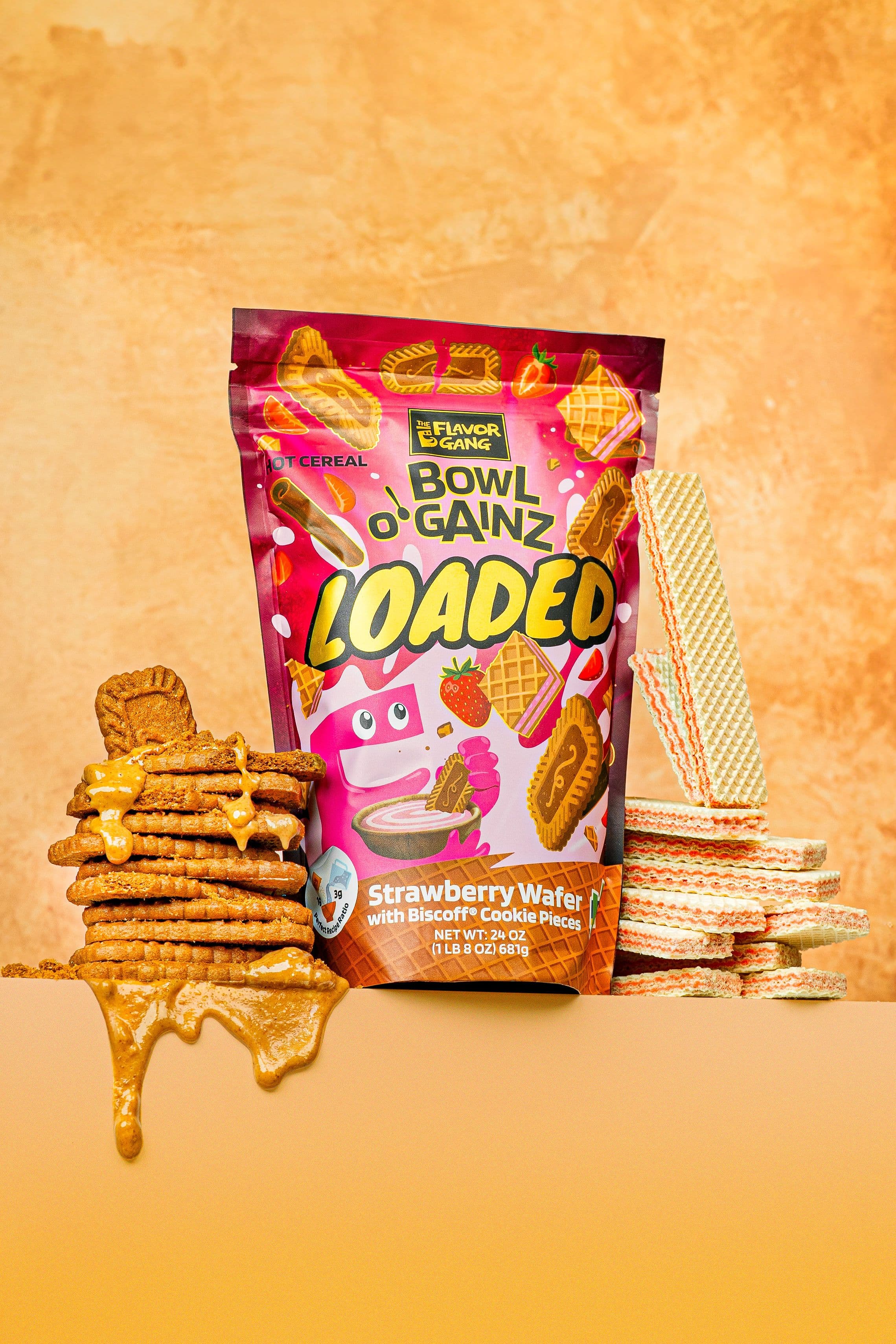 The Flavor Gang Bowl o’ Gainz Loaded Strawberry Wafer hot cereal bag displayed with stacked wafer cookies, Biscoff-style cookies, and melted cookie butter on an orange background.