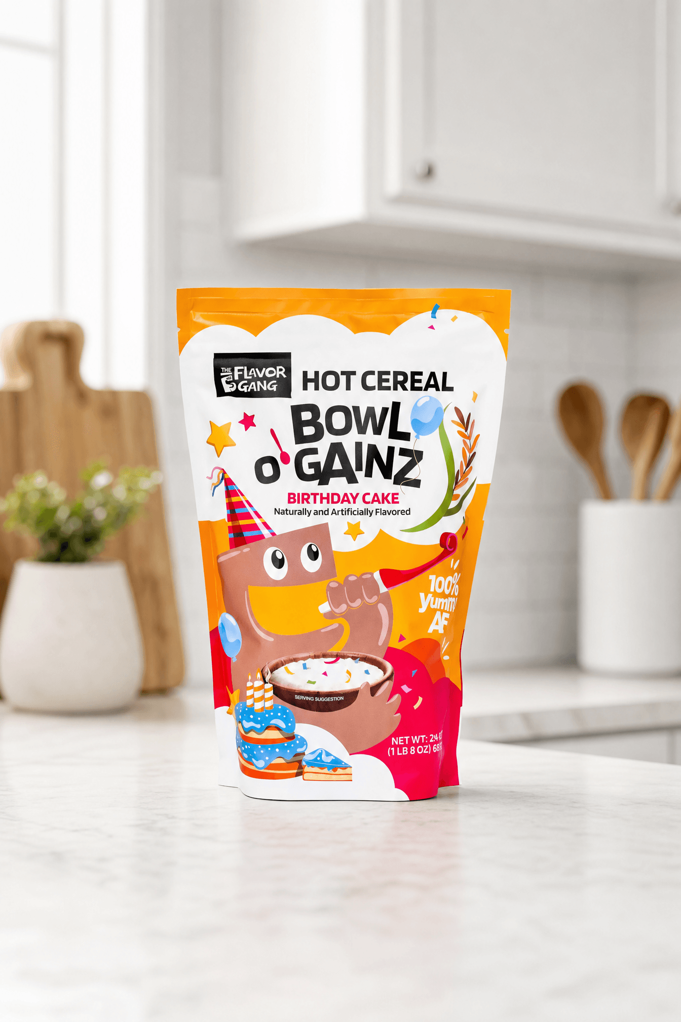 The Flavor Gang Bowl O' Gainz Birthday Cake hot cereal pouch standing on a white marble kitchen counter, featuring a cartoon mascot in a party hat and a serving suggestion of creamy cream of rice topped with rainbow sprinkles.